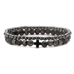Close-up of punk style beaded bracelet set featuring grey stones and a cross charm