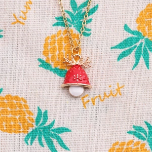 Christmas necklace with red bell pendant and golden antlers on decorative fruit cloth