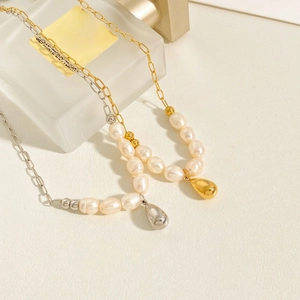 Detail of gold and silver teardrop pendant pearl necklaces on beige textured background