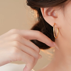 Close-up of elegant gold geometric hoop earrings on model with high gloss finish