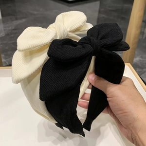 Detail of wide corduroy headbands featuring large rabbit ear bows in black and beige