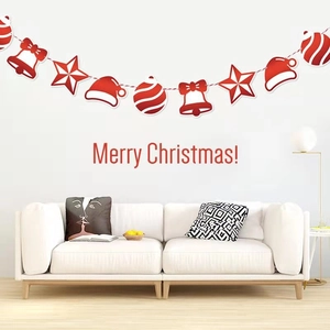 Merry Christmas paper banner with red bells and stars hanging above a white sofa