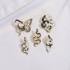 Set of five vintage snake enamel pins in gold and black on white canvas background