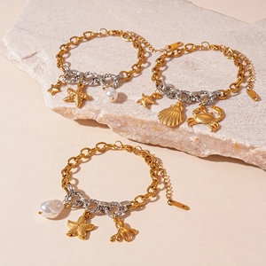 Three gold and silver ocean charm bracelets with sea stars and pearls on stone