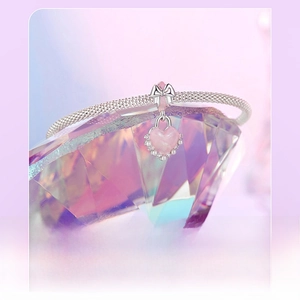 Macro shot of silver bow and pink heart lock pendant on a crystal stone background