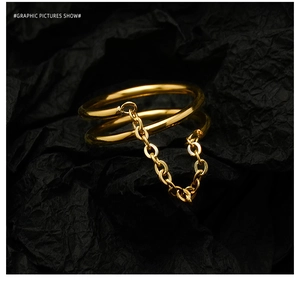 Macro view of double-layered gold ring with fine chain on textured black background