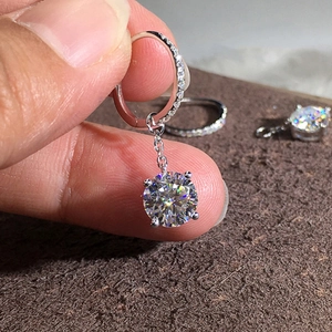 Silver hoop earrings with four-prong round zircon and pavé crystal accents shown in hand