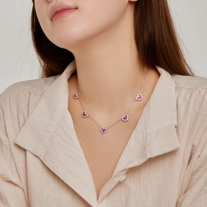 Close-up of S925 silver necklace with five heart pendants and pink gemstones on a model
