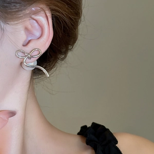 Detail of 14K gold plated bow earrings with white pearls on a model earlobe