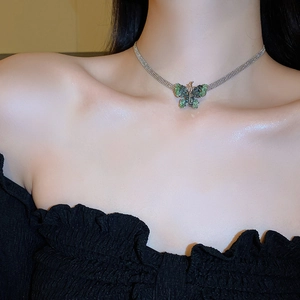 Close-up of a silver butterfly necklace with dark green crystal and sparkling diamonds
