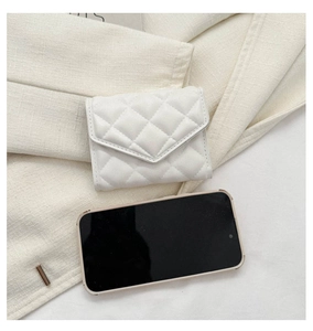 Top view of a white quilted PU leather fold wallet next to a smartphone for size reference