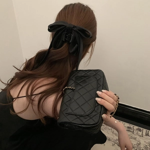 Detail of elegant black satin bow claw clip on long hair for a sophisticated look