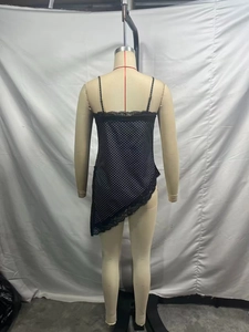 Detail of black polka dot camisole featuring delicate lace trim and an asymmetric hemline