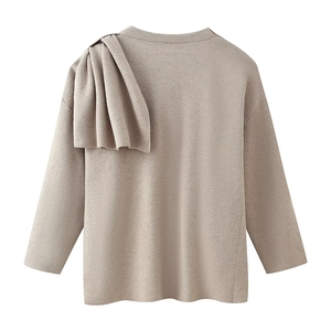 Detail of the oversized ruffled shoulder and delicate knit texture of this beige top