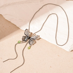 Detail of silver box chain necklace featuring butterfly pendant with green drop crystals