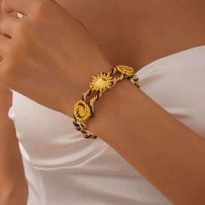 Detailed macro view of woven black and white rope with gold sunflower metal charm
