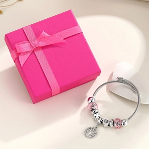 Detail of silver crown charm bracelet with pink beads and tree of life in a gift box