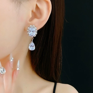 Detail view of pear-shaped silver zircon earrings on model with elegant black background