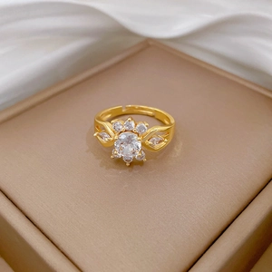 Detailed macro view of a gold floral ring with leaf design and a bright zircon center