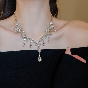 Close-up of sparkling leaf and pink teardrop gemstone necklace with elegant tassel fringe