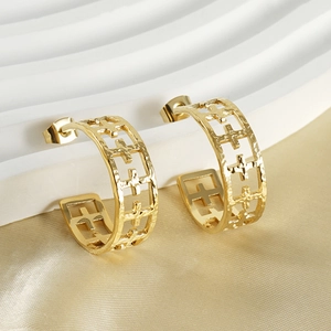 Detail of gold hollow cross earrings on silk background with soft lighting