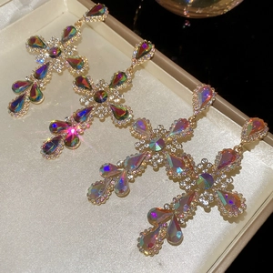 Detail of cross earrings with iridescent rhinestones and gold base in a jewelry box