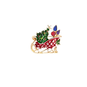Detail showing a golden Christmas sleigh brooch with colorful rhinestones and enamel tree