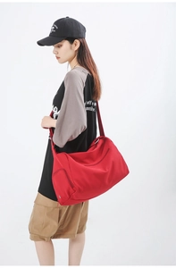 Détail d'un grand sac de sport rouge avec poche latérale porté par un mannequin