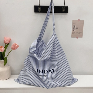 Detail of blue and white striped canvas bag with Sunday Summer Night text hanging on a hook
