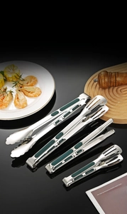 Detail of stainless steel food tongs with green non-slip handles and various head designs