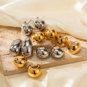 Macro view of teardrop earrings in polished gold and silver finish on silk