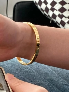 Close-up of a gold-plated titanium steel starburst bangle worn on the wrist