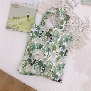 Détail du petit sac en toile à imprimé feuillage vert avec fermeture à bouton pression