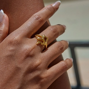 Detailed close-up of a golden coral-shaped stainless steel ring worn on a finger