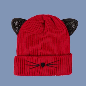 Detail of red knit beanie with cute cat ears featuring black sequins and embroidered face