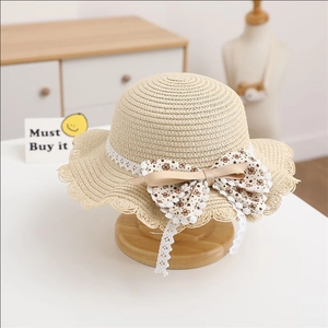 Detailed view of kids' straw sun hat with floral bow and white lace trim decoration