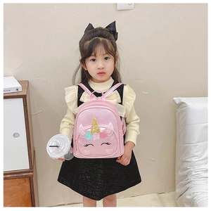 Close-up of pink unicorn backpack with sequins and floral details on a young girl