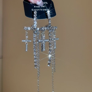 Macro shot of silver cross earrings with sparkling tassels and rhinestone details