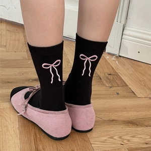 Close-up of black mid-calf socks with pink embroidered bow and sweet ruffle edge