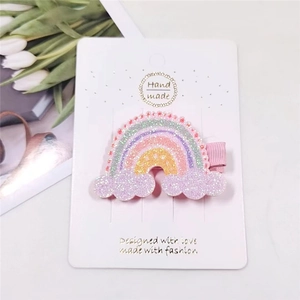 Detail of glitter rainbow hair clip with purple clouds on white display card