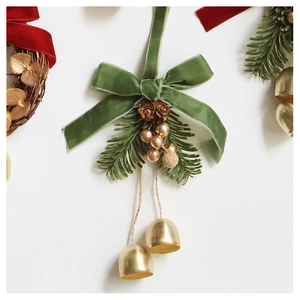 Detail of velvet bow with golden bells and pine cone on a Christmas hanging ornament