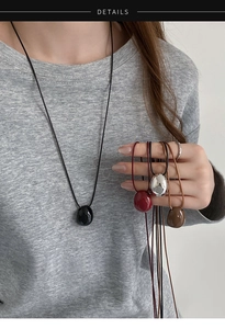 Detailed view of irregular pebble pendants in multiple colors worn by a model