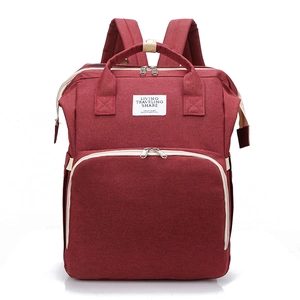 Close-up of a burgundy multifunctional diaper bag with reinforced handles and travel label