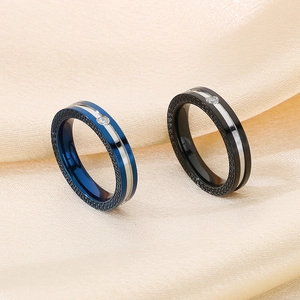 Detailed view of blue and black stainless steel rings with Greek key pattern and crystals