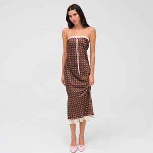 Detailed view of brown polka dot dress featuring pink ribbon and white lace trim