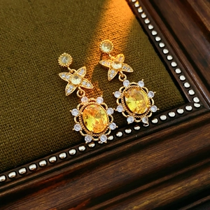 Detailansicht goldener Vintage-Ohrringe mit großen gelben Zirkonia und klaren Kristallblüten