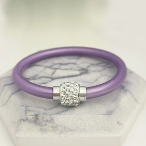 Nahaufnahme von lila Silikonarmband mit strassbesetztem silbernem Metallrohr