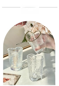 Detail of heart-shaped glass with hammer texture and gold rim held by a hand
