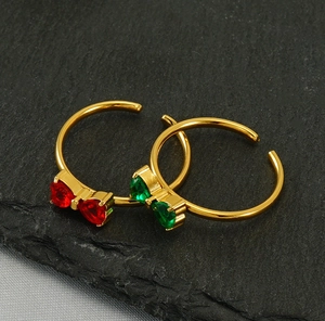 Macro d'anneaux dorés avec nœuds en zircone en forme de cœur rouge et vert sur pierre
