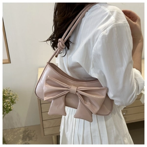 Close-up of the large bow detail on a glossy patent leather underarm shoulder bag